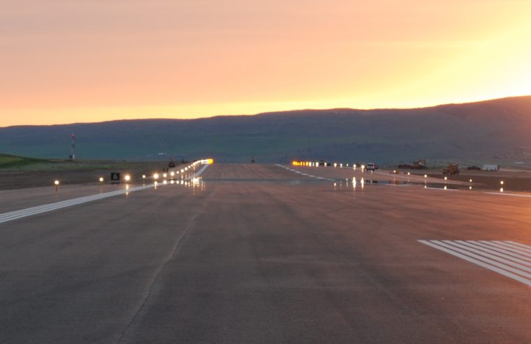 Yampa Valley Regional Airport runway at sunset with the sun peaking over a mountain in the background.